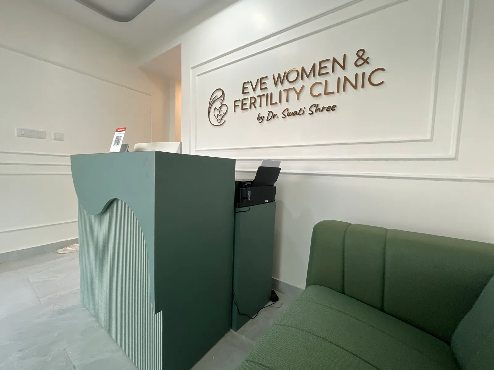 Clinic reception desk and green waiting-room seating beneath the EVE wall sign.