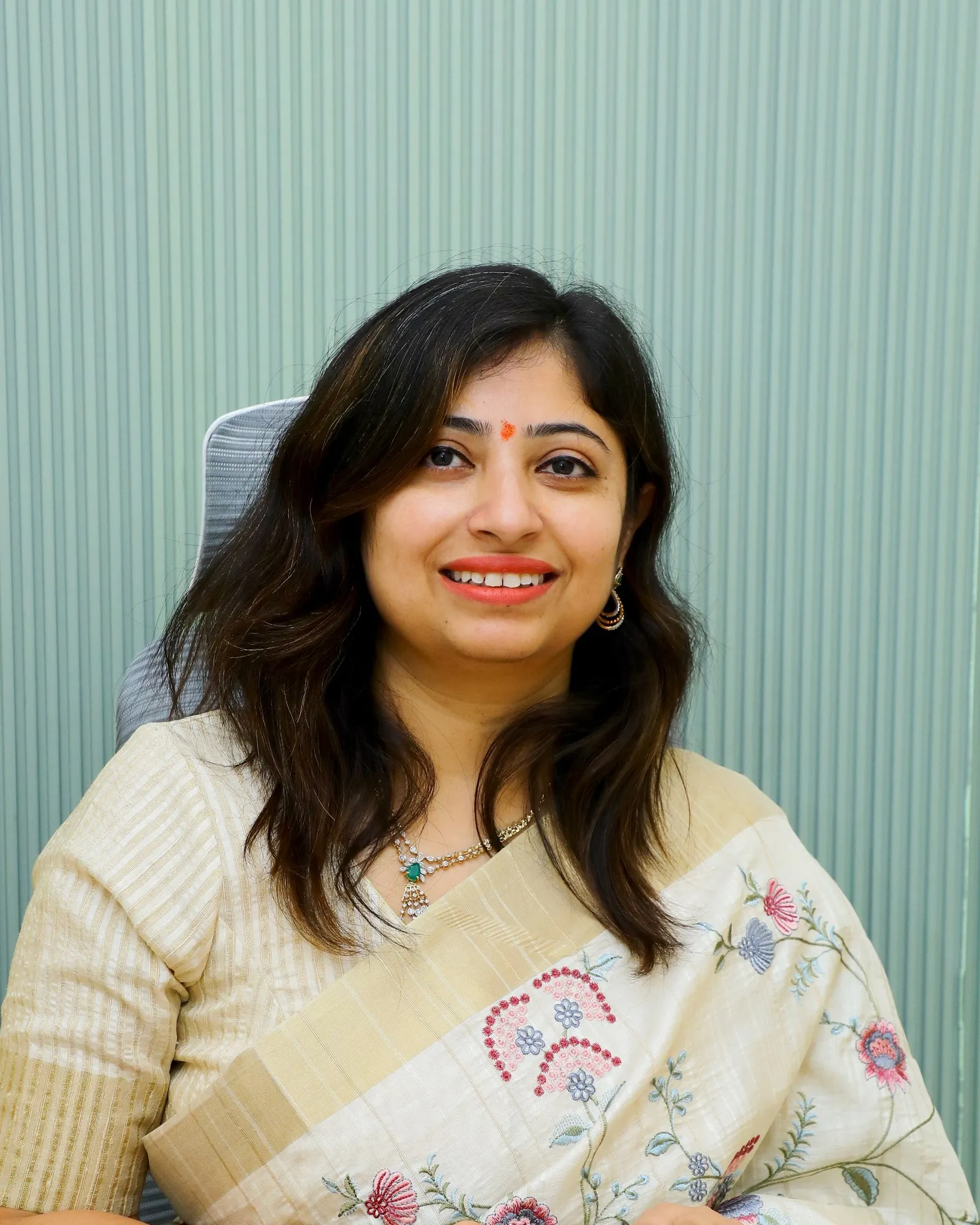 Dr. Swati Shree in a cream saree against a sage panel.